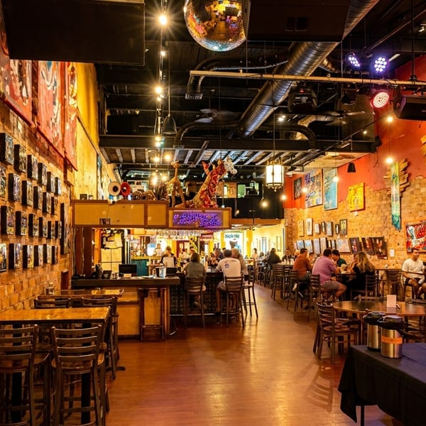Vibrant restaurant interior with brick walls, eclectic art, a disco ball, and patrons dining.