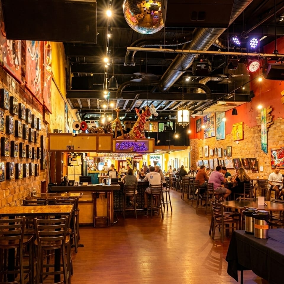 Vibrant restaurant interior with brick walls, eclectic art, a disco ball, and patrons dining.